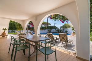 een patio met een tafel en stoelen en een zwembad bij Traditional 3 bedroom villa with great pool in the heart of Vale do Lobo in Vale do Lobo