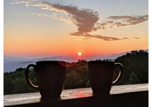 dos tazas de café sentadas en el alféizar de la ventana con la puesta de sol en SKY HIGH VIEWS!!-Peak Mountaintop-Outdoor Pool-Close to Downtown-Private Balcony-WiFi-Cable, en Gatlinburg