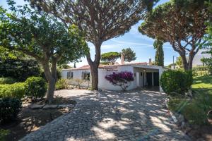 una casa blanca con árboles y un camino de entrada en Traditional 3 bedroom villa with great pool in the heart of Vale do Lobo en Vale do Lobo