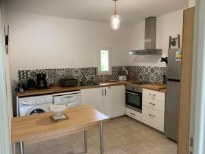 cocina con electrodomésticos blancos y mesa de madera en Gîte Bastide LAGREMUSE, en Sarrians