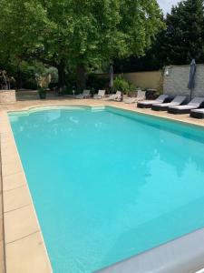 una gran piscina azul con sillas y árboles en Gîte Bastide LAGREMUSE, en Sarrians