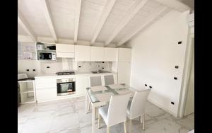 eine weiße Küche mit einem Glastisch und weißen Stühlen in der Unterkunft Superior apt Colico Lake Como in Colico