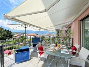 eine Terrasse mit einem Tisch, Stühlen und einem Sonnenschirm in der Unterkunft Superior apt Colico Lake Como in Colico