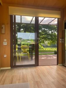 una puerta de cristal abierta con mesa y sillas amarillas en BIG BERRY Kolpa - Isabella Premium House, en Gradac