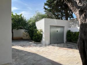 a white building with a door and a tree at Villetta Trama- Spiaggia a 100m in Porto Cesareo