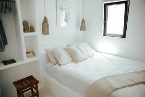 a white bedroom with a bed and a window at Sol living in Tinos