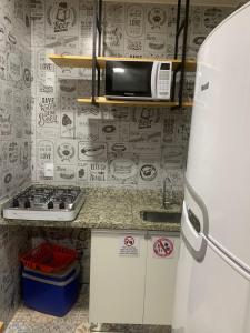 a small kitchen with a refrigerator and a microwave at Lagoa Quente Flat Service in Caldas Novas