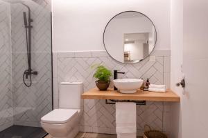 W łazience znajduje się umywalka, toaleta i lustro. w obiekcie apartamentos junto a jardines del triunfo w Grenadzie