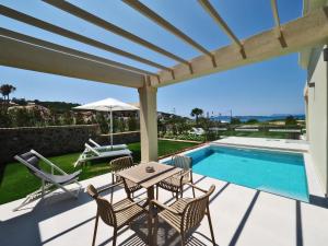 een patio met een tafel en stoelen en een zwembad bij Hotel Athina in Agios Stefanos