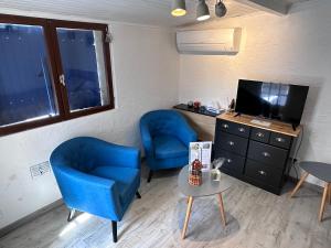 a living room with two blue chairs and a tv at Studio les Iris climatisé, entre mer et collines, classé meublé de tourisme 2 étoiles in Allauch