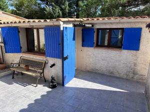 une maison avec des portes bleues et un banc sur une terrasse dans l'établissement Studio les Iris climatisé, entre mer et collines, classé meublé de tourisme 2 étoiles, à Allauch