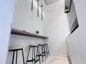 Una fila de taburetes en una habitación blanca con un televisor. en Zeus Design Apartment Schlosspark Schönbrunn, en Viena