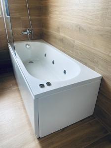 y baño con bañera blanca y paredes de madera. en Apartamentos Palacio Alemar, en Loredo