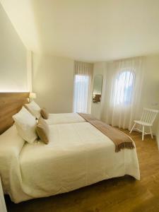 Un dormitorio con una gran cama blanca y una ventana en Apartamentos Palacio Alemar, en Loredo