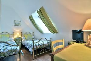 um quarto com duas camas e uma televisão e uma janela em Cap Frehel gîte 4 personnnes em Frehel