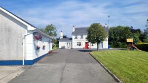 a white house with a driveway next to a yard at Murray's Lodge: Self-Catering Accommodation. in Cavan