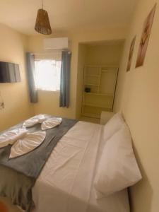 a bedroom with a bed with white sheets and a window at Residencial Terrazas in Florianópolis