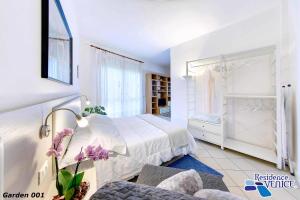 una camera bianca con un letto e una sedia di Residence Venice a Quarto dʼAltino