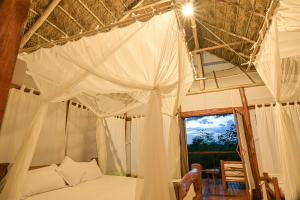 Kazinga Wilderness Safari Camp في كاسيزي: غرفة نوم مع سرير مظلة مع نافذة