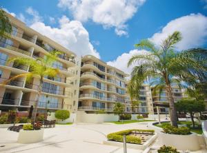 un gran edificio de apartamentos con palmeras enfrente en 2 BR Apartment - Pool & jacuzzi, en Cancún