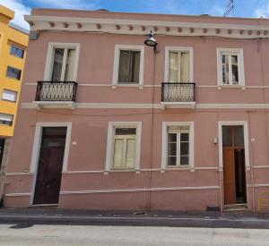um edifício cor-de-rosa com janelas e uma varanda em Dani's House em Cagliari