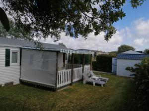 uma casa branca com uma cerca e dois bancos em MOBIL HOME dans Parc résidentiel Loisirs em Talmont