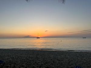 una puesta de sol en la playa con un barco en el agua en Seacret Studios - Cozy Jamaican Retreat apts, en Negril