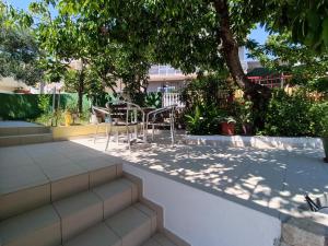 a patio with a table and chairs under a tree at Apartment Ema in Zadar