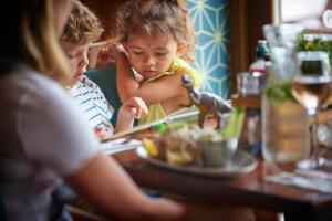 un grupo de niños sentados en una mesa comiendo comida en Hunters Quay Holiday Village, en Kilmun