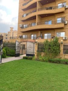 a building with a balcony and a grass yard at Luxury Apartments Beside Mall of Arabia and Dar Al-Fouad hospital - Families only- No Alcoholic Beverages in 6th Of October