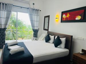 a bedroom with a bed and a window with a view at Liyonaa Beach Hotel in Trincomalee