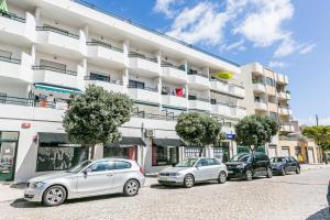 uma fileira de carros estacionados em frente a um prédio em 1 Bedroom Beach Apartment with Balcony 2 min walk to the beach! em Costa da Caparica