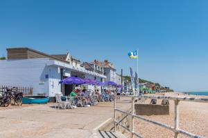 un grupo de personas sentadas bajo sombrillas en una playa en Seagulls by Bloom Stays en Folkestone