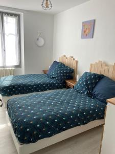 - une chambre avec 2 lits avec des draps bleus et une fenêtre dans l'établissement GITE DE LA CAZELLERIE, à Feings