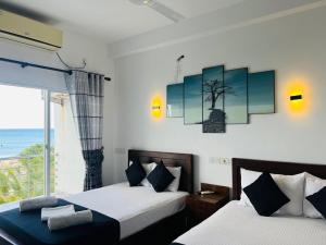 two beds in a room with a view of the ocean at Liyonaa Beach Hotel in Trincomalee