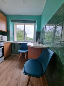 a kitchen with two blue chairs and a counter at Entire apartment in Pakruojis in Pakruojis