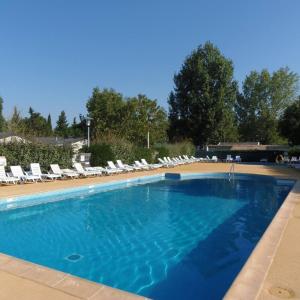 a large swimming pool with lounge chairs at CAMPING LE NAVARRE *** in Vias