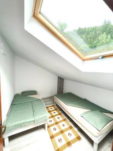 deux lits dans une chambre avec une fenêtre dans l'établissement Gyimesi kulcsosház / Casa de vacanta Ghimes, à Lunca de Sus