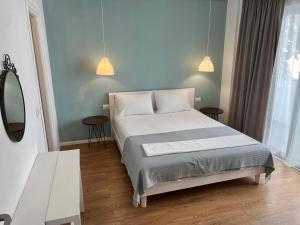 a bedroom with a bed and two tables and a mirror at Kanes Boutique Hotel in Sarandë