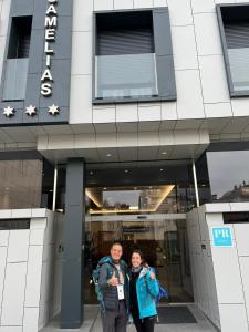 dos personas parados frente a un edificio en Praza Camelias, en Sarria