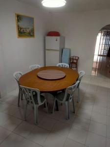 Sibu kulas homestay في سيبو: طاولة خشبية مع كراسي وثلاجة في الغرفة