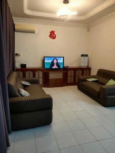Sibu kulas homestay في سيبو: غرفة معيشة مع كنبتين وتلفزيون بشاشة مسطحة