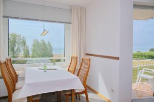 ein Esszimmer mit einem Tisch und Stühlen sowie einem großen Fenster in der Unterkunft Hanseat II App 148 in Grömitz