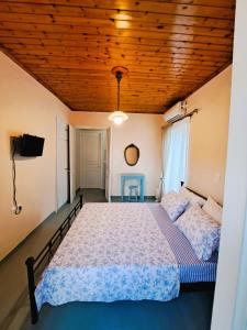 Giasemi traditional house في بوروس: غرفة نوم بسرير وسقف خشبي