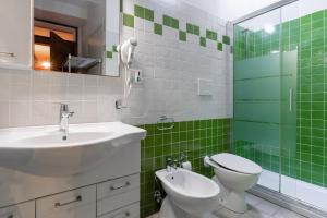 a green and white bathroom with a sink and a toilet at Appartamento Sottosopra in Gallipoli +19 photos