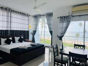 a bedroom with a bed and a table and chairs at Liyonaa Beach Hotel in Trincomalee