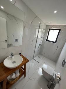 a white bathroom with a sink and a toilet at Kanes Boutique Hotel in Sarandë