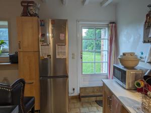 Il comprend une cuisine équipée d'un réfrigérateur en acier inoxydable et une fenêtre. dans l'établissement Cottage Tranquillité, à Genouillac
