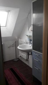 La salle de bains blanche est pourvue d'un lavabo et d'une fenêtre. dans l'établissement Ferienwohnung Bänsch, à Weischlitz