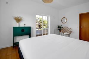 a white bedroom with a large bed and a window at Beautiful Villa in Sunny Lagoa in Sesimbra